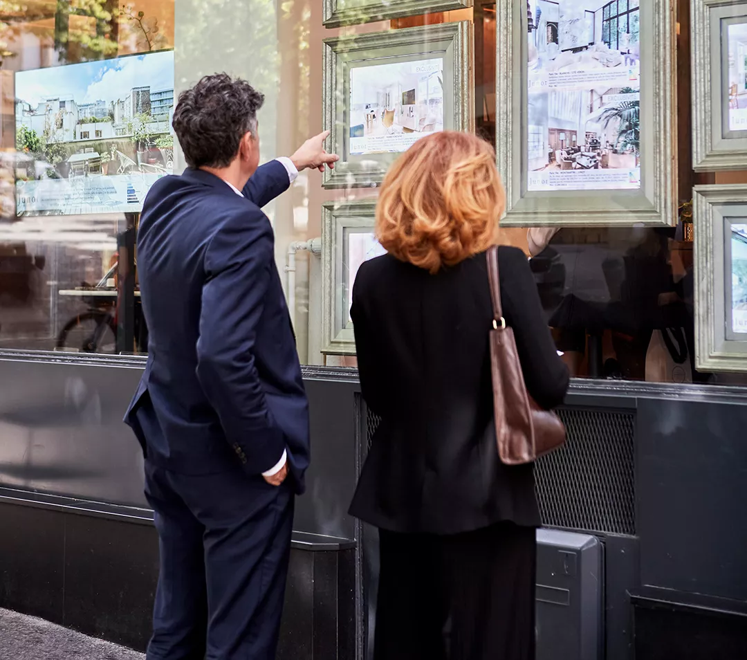 Un homme et une femme qui regardent la vitrine d'une agence Junot