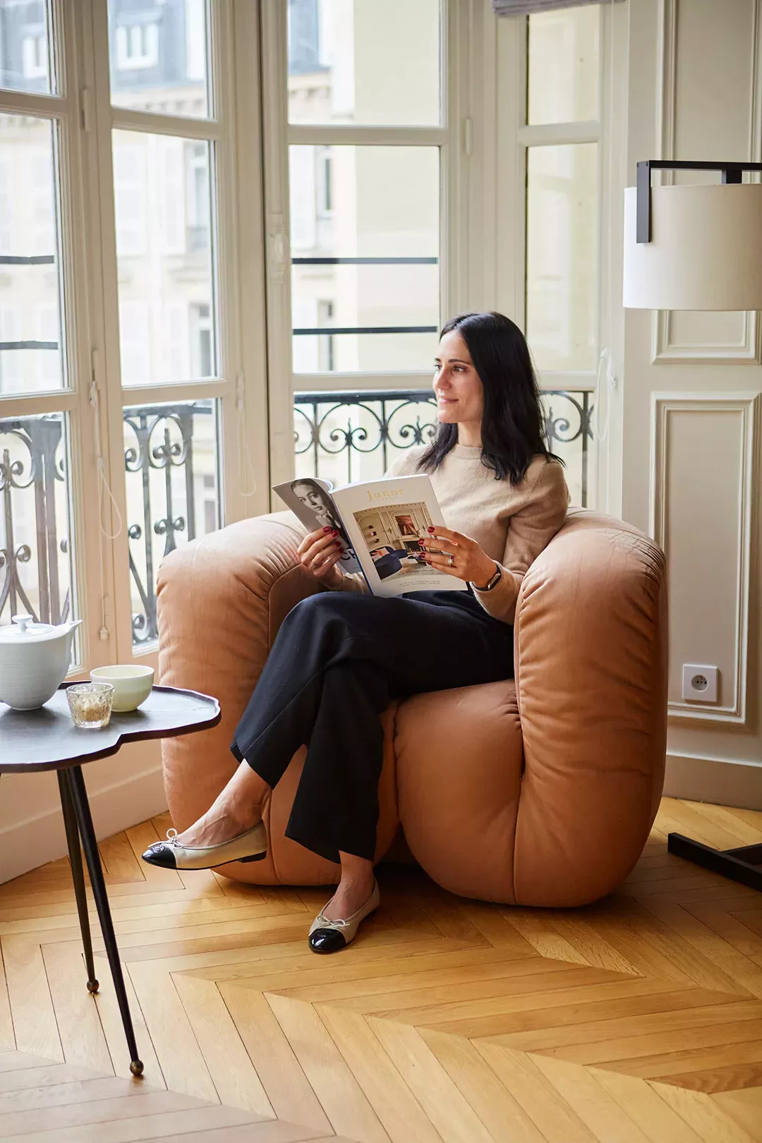 Femme lisant le Junot Magazine Assise sur un fauteuil marron