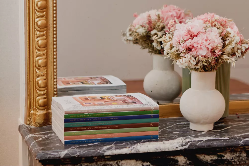 Les huit magazines Junot posés sur une cheminée en marbre